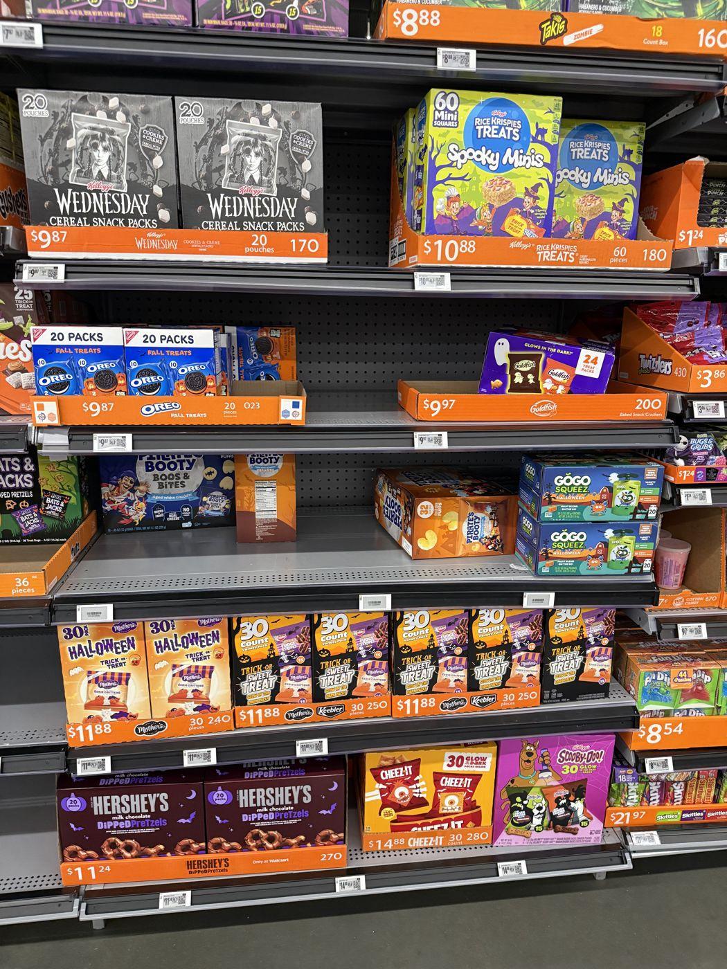 Walmart seasonal shelves with Rice Krispies Treats Spooky Minis, Oreo, Cheez-It, Wednesday cereal snack packs and Hershey's dipped pretzels